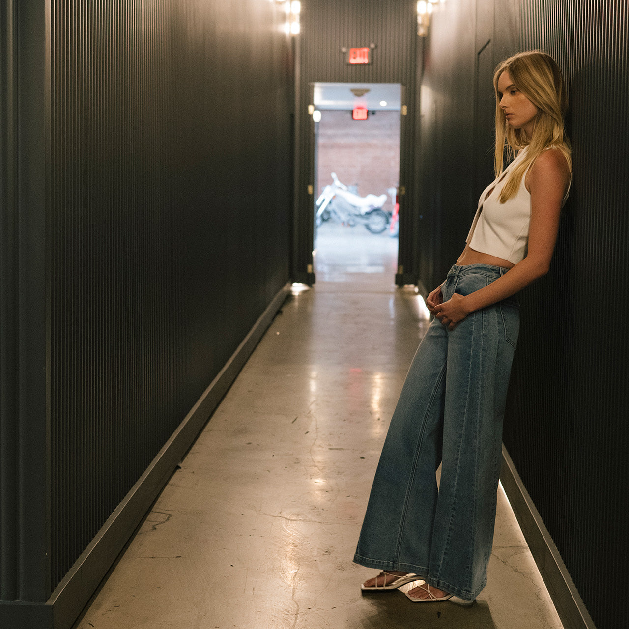 Model wearing Flying Monkey women's jeans leaning against a wall. Shop all denim.